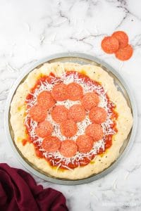 whole uncooked pepperoni pizza. Thick crust pizza dough with pizza sauce, cheese and pepperoni.