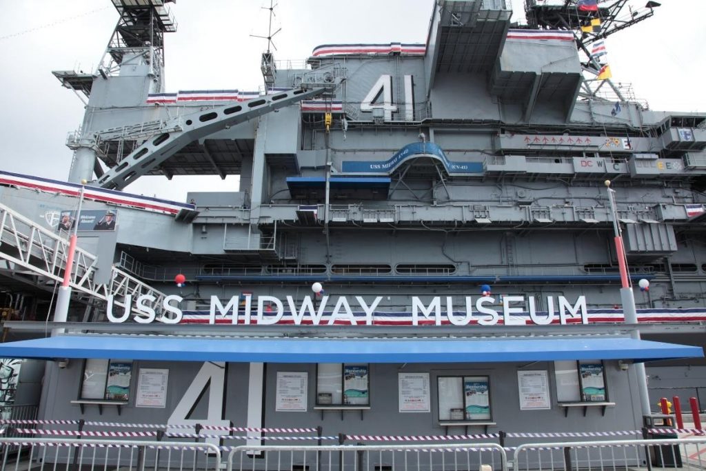 USS Midway Museum entrace with 4 ticket windows in front of the giant aircraft carrier