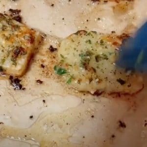 blue basting brush brushing tiktok potato squares with garlic butter on parchment paper