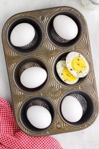 Muffin tin full of cooked eggs in the shell.