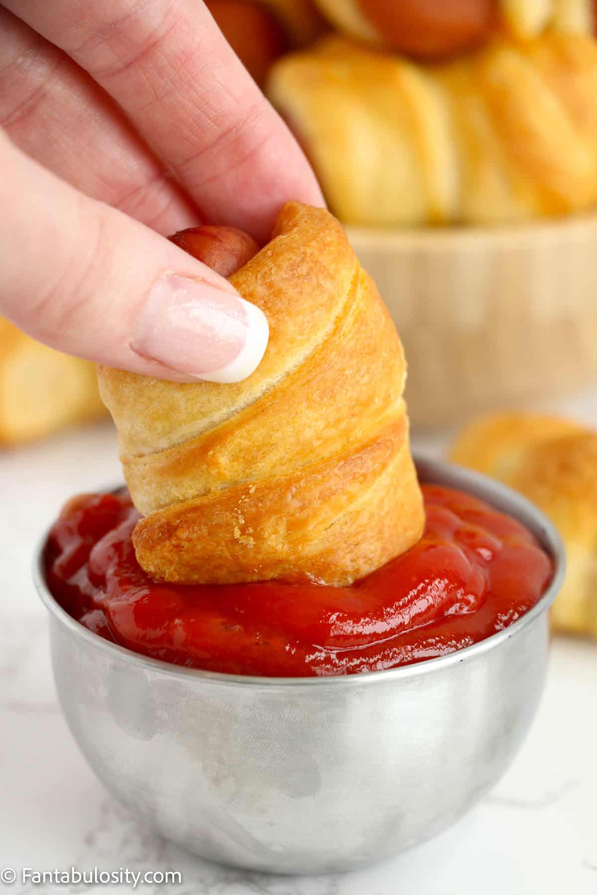 Pigs in a blanket dipped into ketchup.