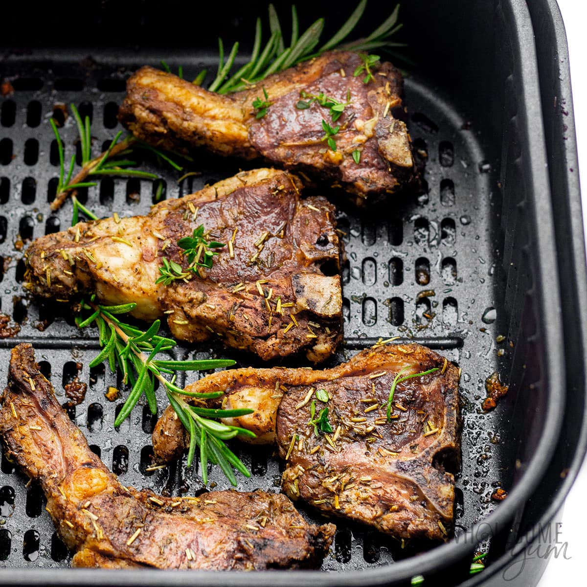 Lamb chops in an air fryer basket.