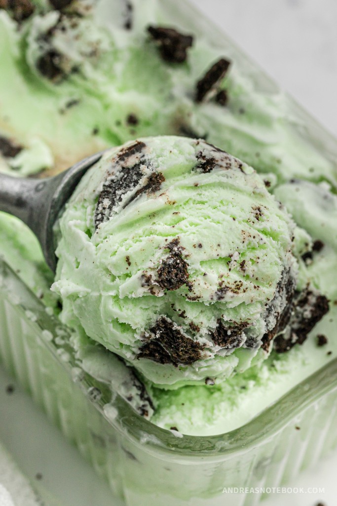 Scooping mint oreo cookie ice cream out of a loaf pan.