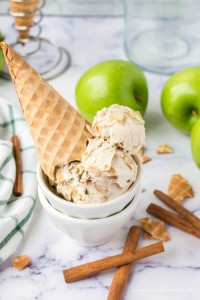 Apple pie ice cream scoops in a bowl with waffle cone on top.