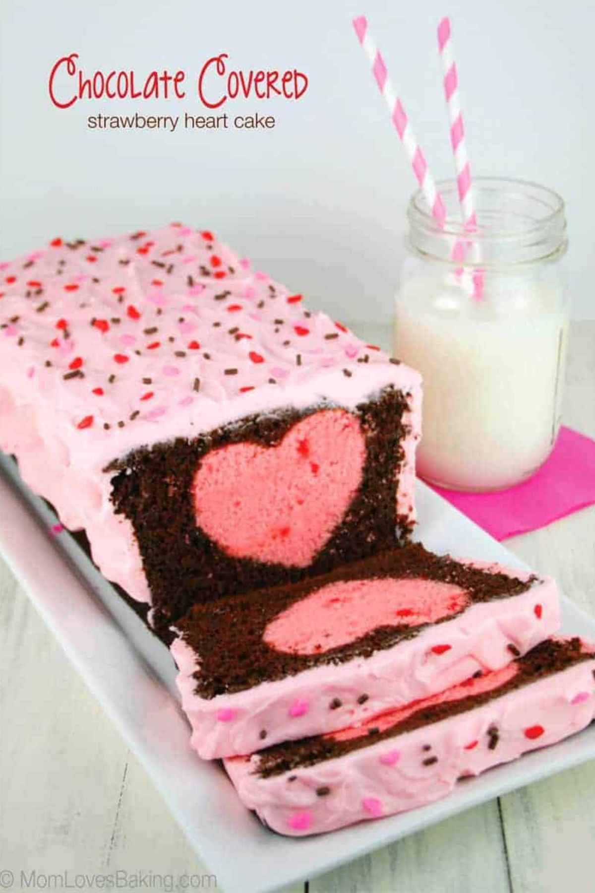 Loaf cake with pink frosting and a pink heart shape surrounded by chocolate cake.