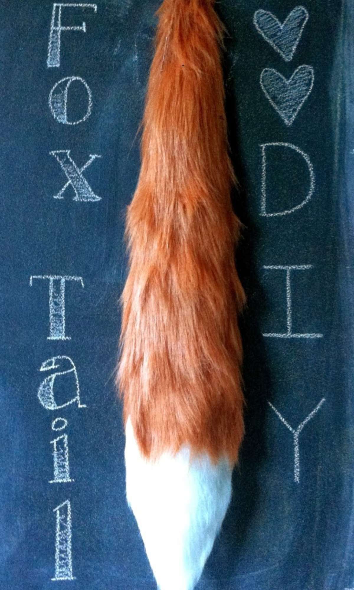 DIY faux fur fox tail with white felt tip hanging on blackboard.