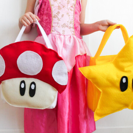 Girl in pink dress holding star treat bag and mushroom DIY treat bag.