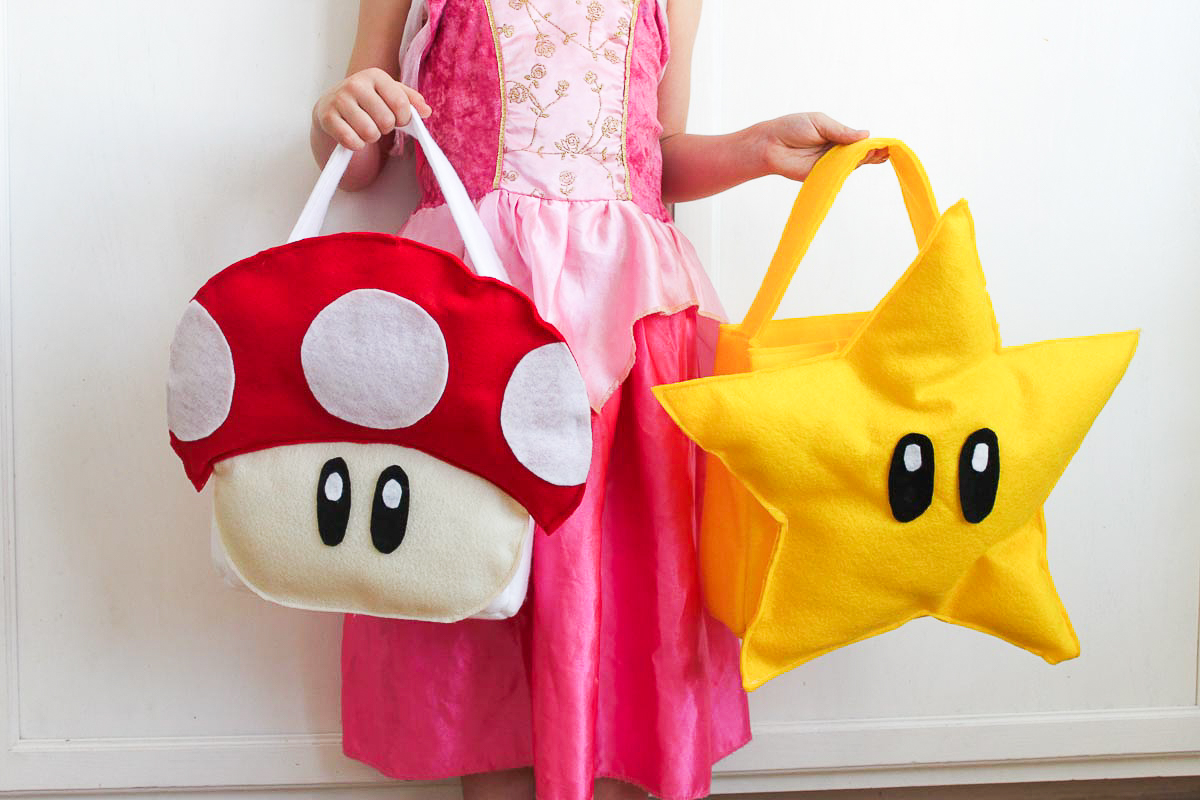 Girl in pink dress holding star treat bag and mushroom DIY treat bag.