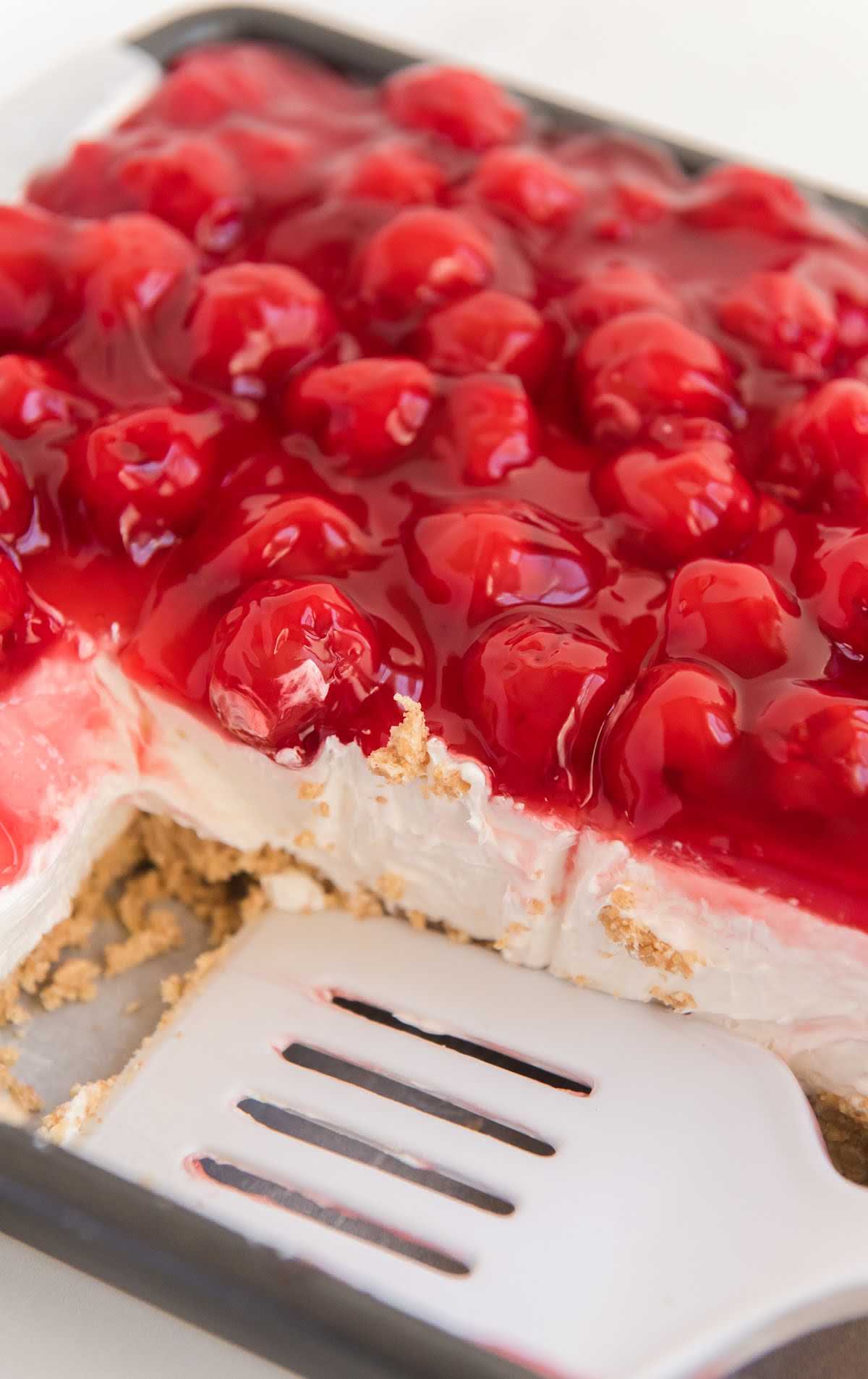 no bake cherry cheesecake in a baking dish with squares missing.