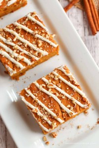 Square pumpkin bars with drizzled icing on a plate.