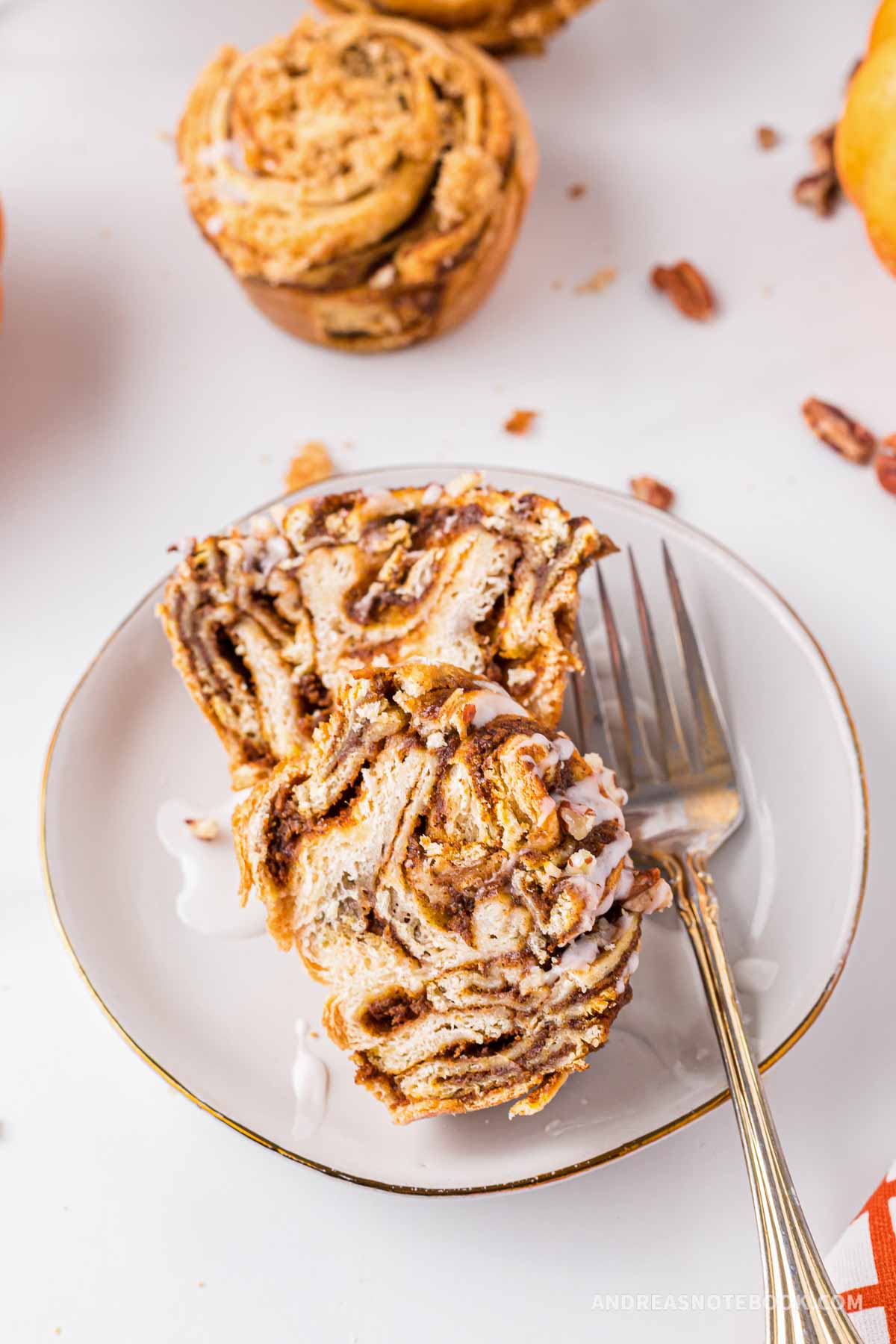 Cinnamon roll muffin cut in half on a plate.