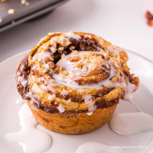 Delicious pumpkin cinnamon roll muffin with glaze drizzled on top.