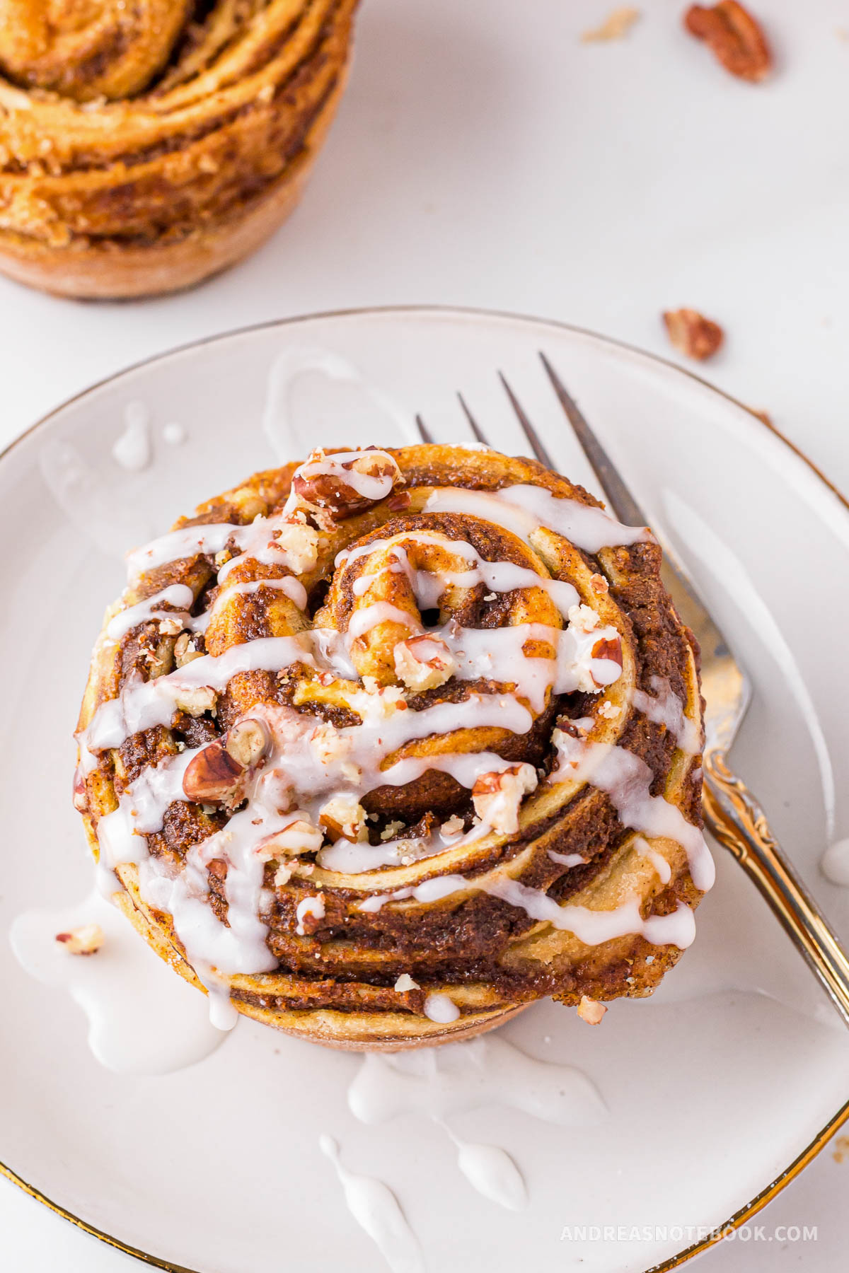 Delicious pumpkin cinnamon roll muffin with glaze drizzled on top.