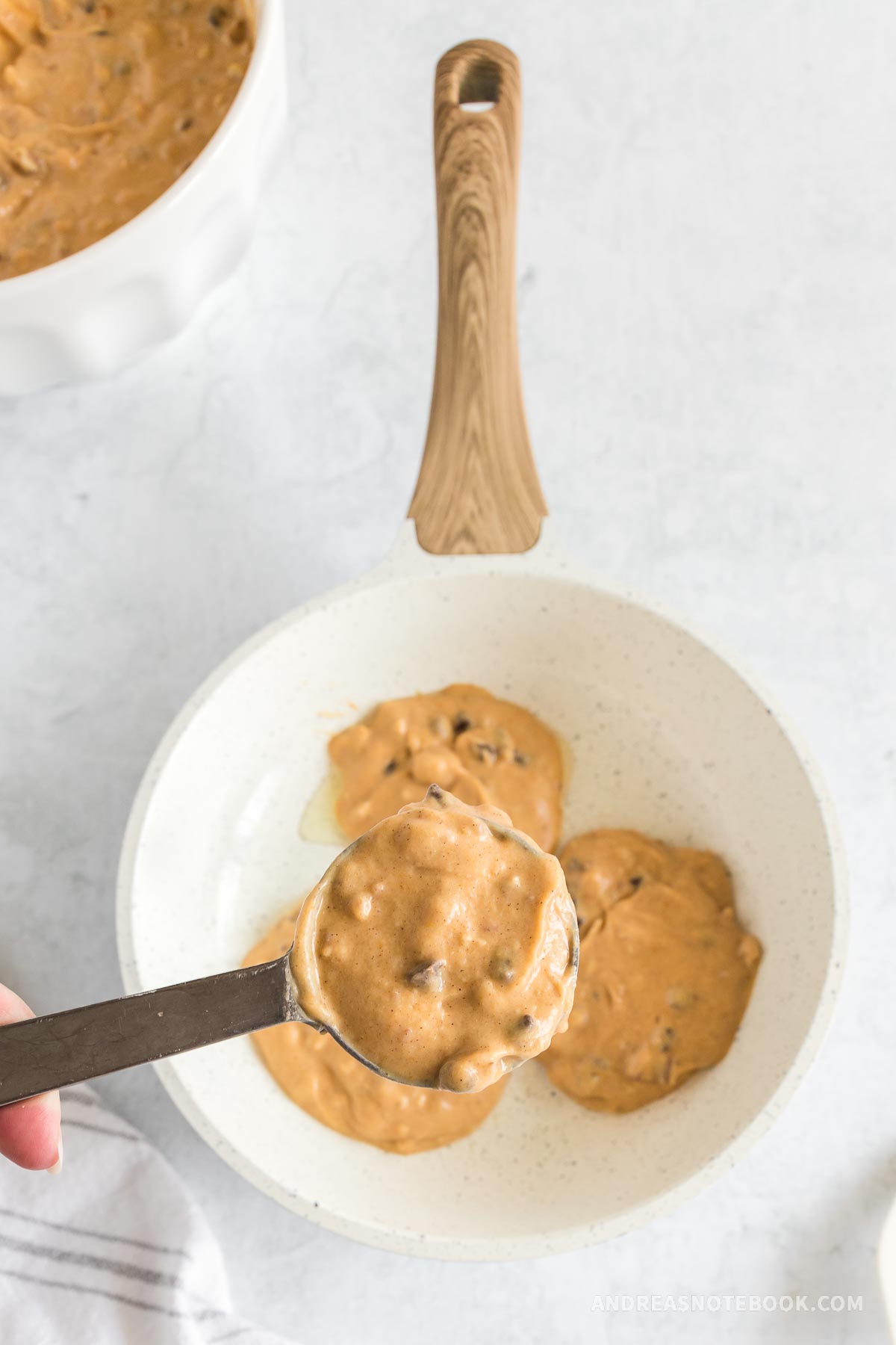 Buttermilk pumpkin pecan pancake batter scooped onto hot skillet.