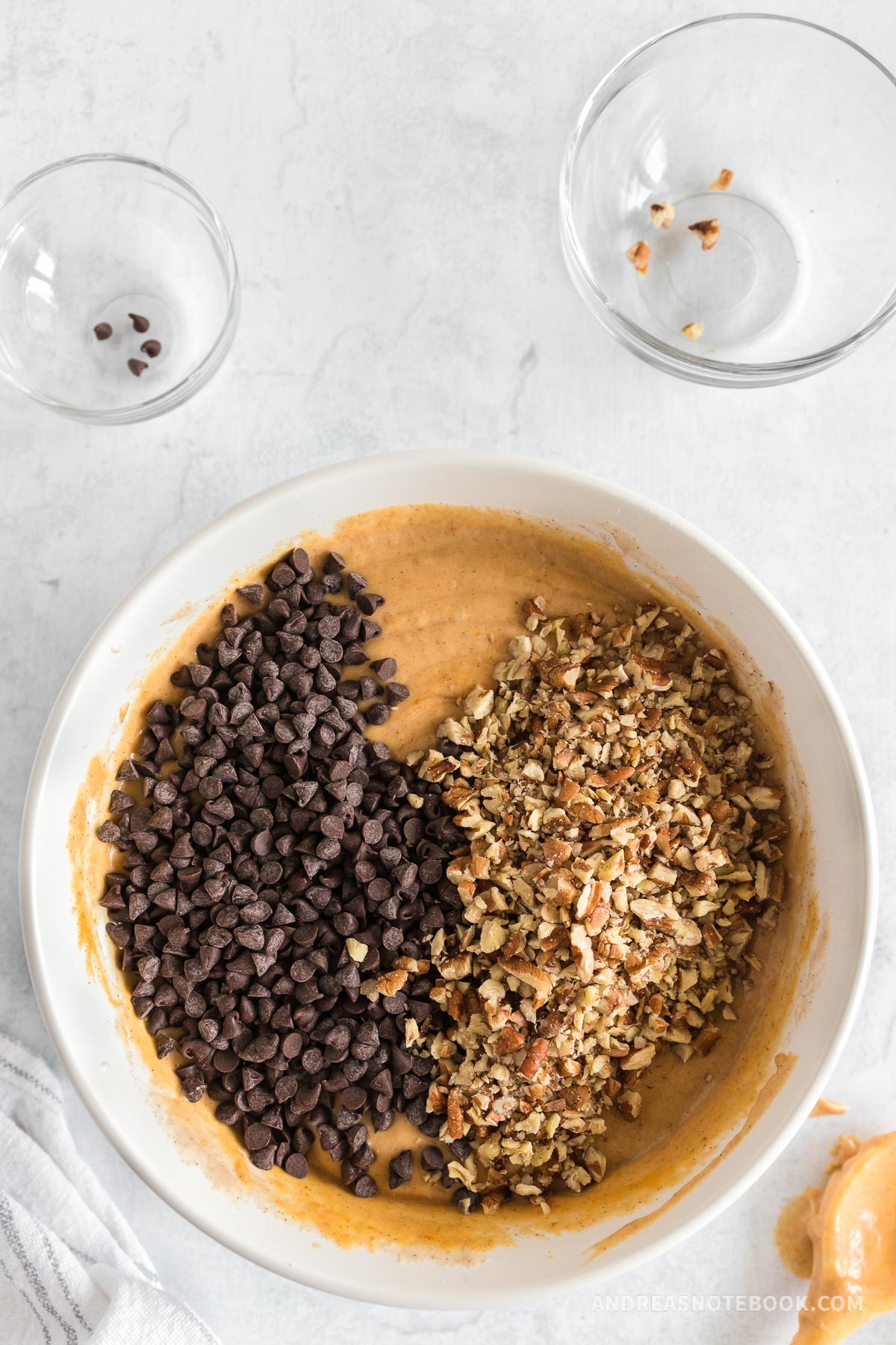 Chocolate chips and pecans in a bowl with pancake batter.