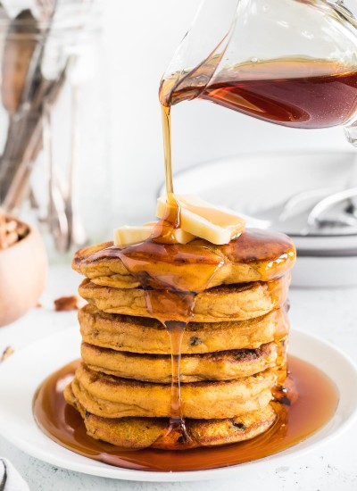 Syrup pouring over pumpkin pecan pancakes.