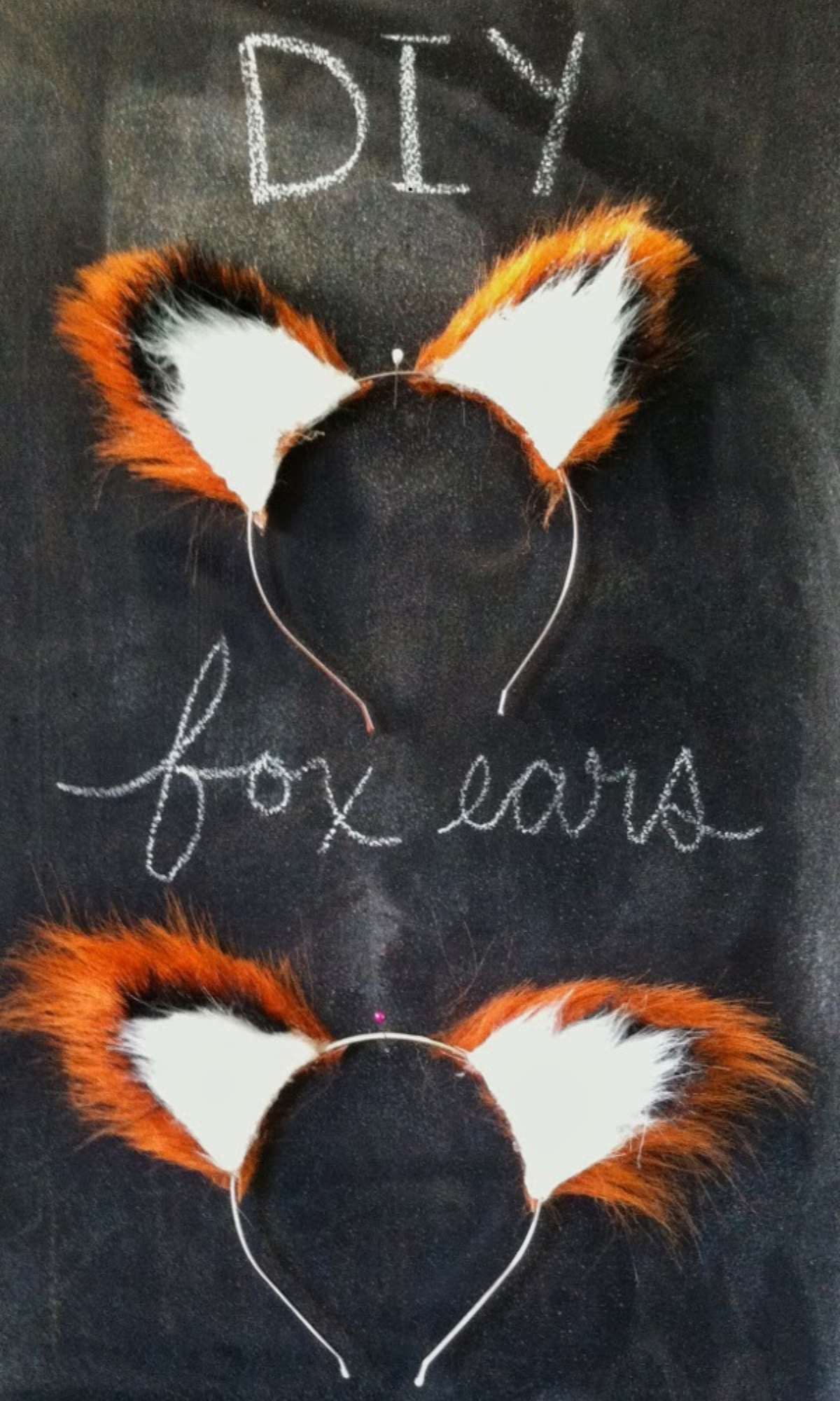 DIY faux fur fox ears on a headband laying on a chalkboard.
