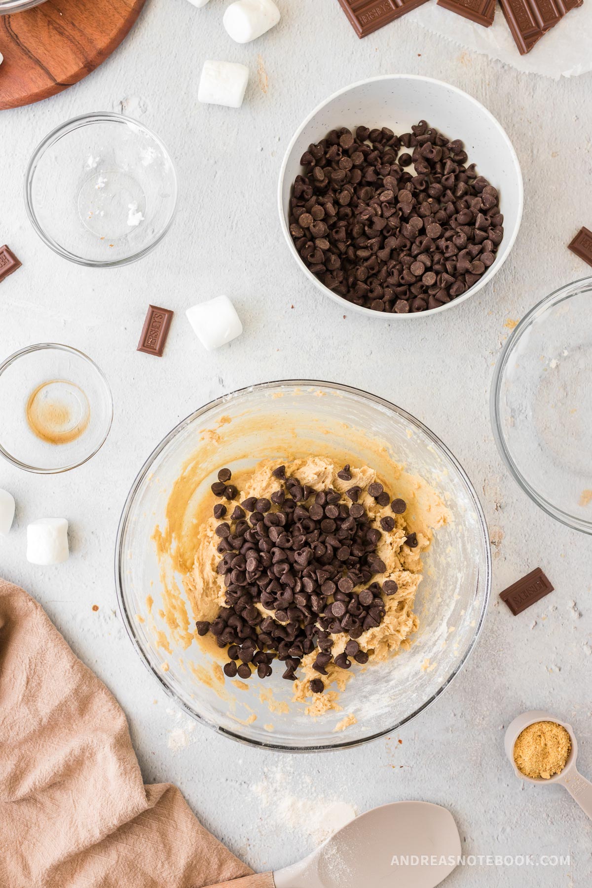 Chocolate chips on top of cookie dough in a large mixing bowl.