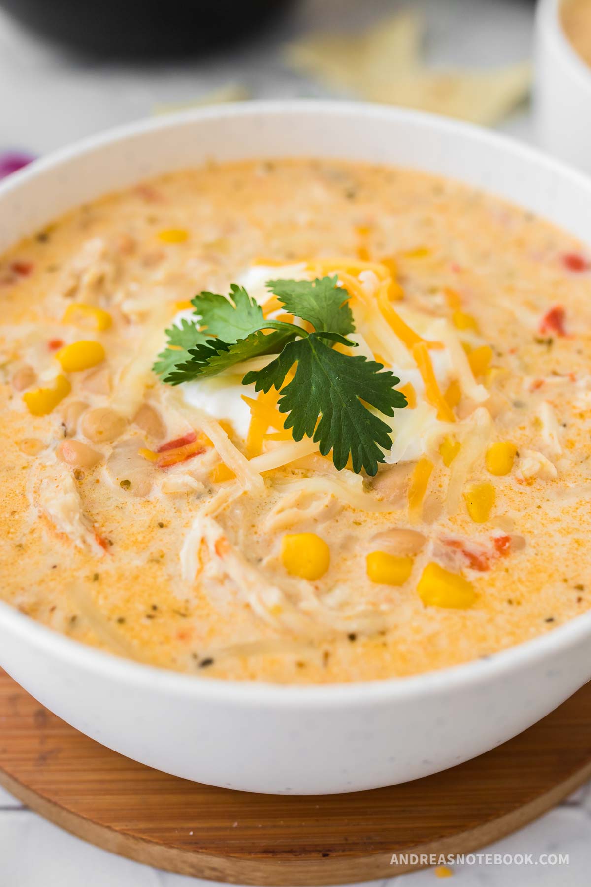 Bowl of white chicken chili with cheese on top.