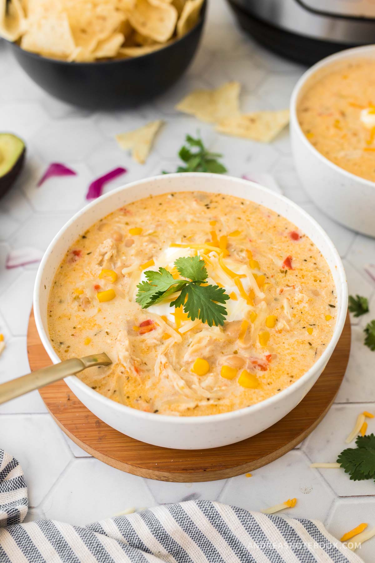 bowl of white chicken chili with cheese, sour cream and cilantro on top.