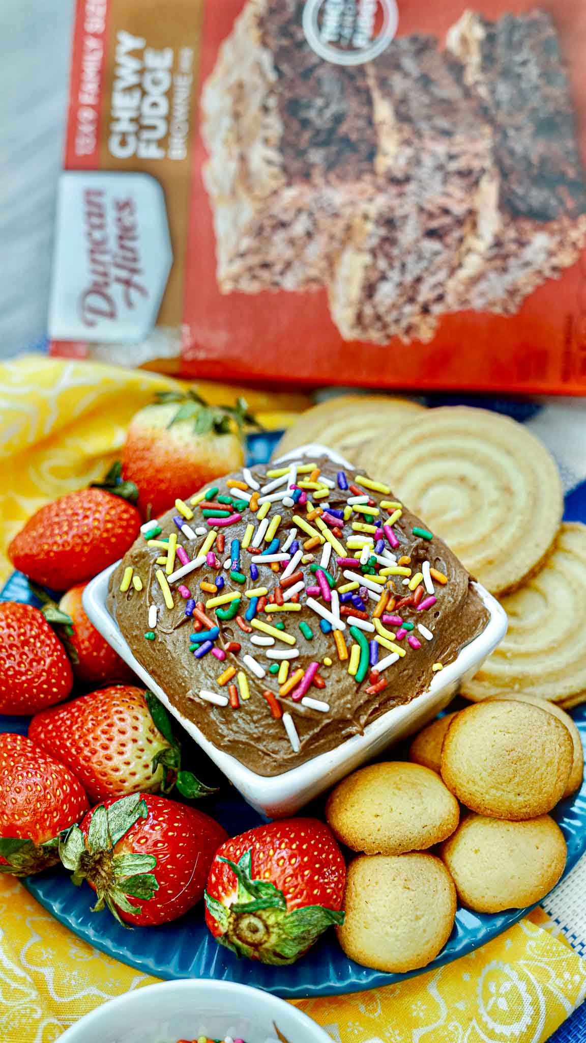 Brownie dip in a bowl surrounded by strawberries and cookies.