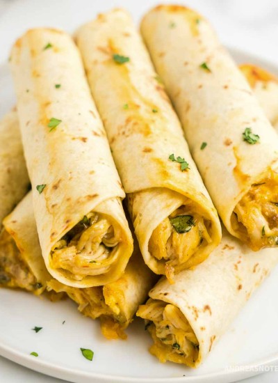 Stacked chicken taquitos on a plate.