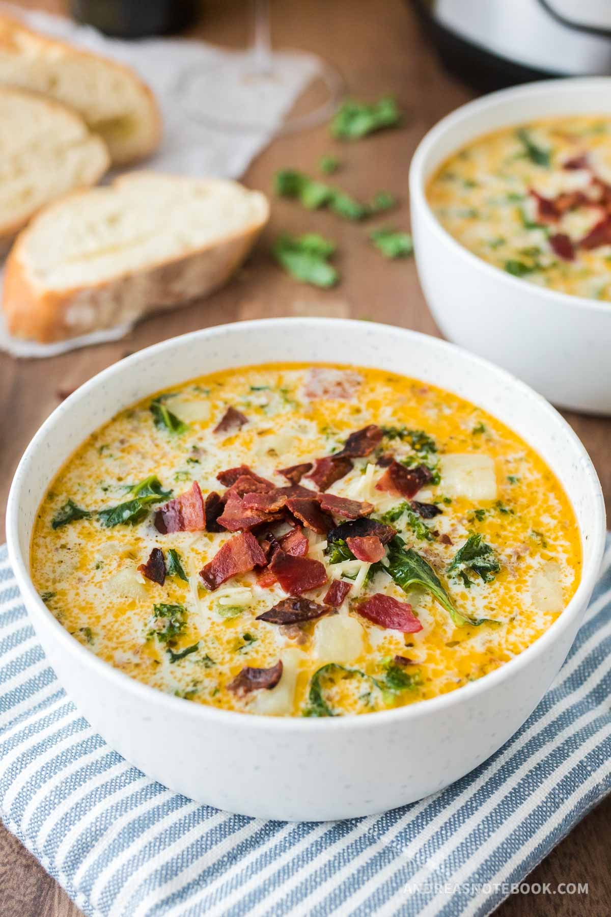 Two bowls of zuppa toscana soup with bacon on top.