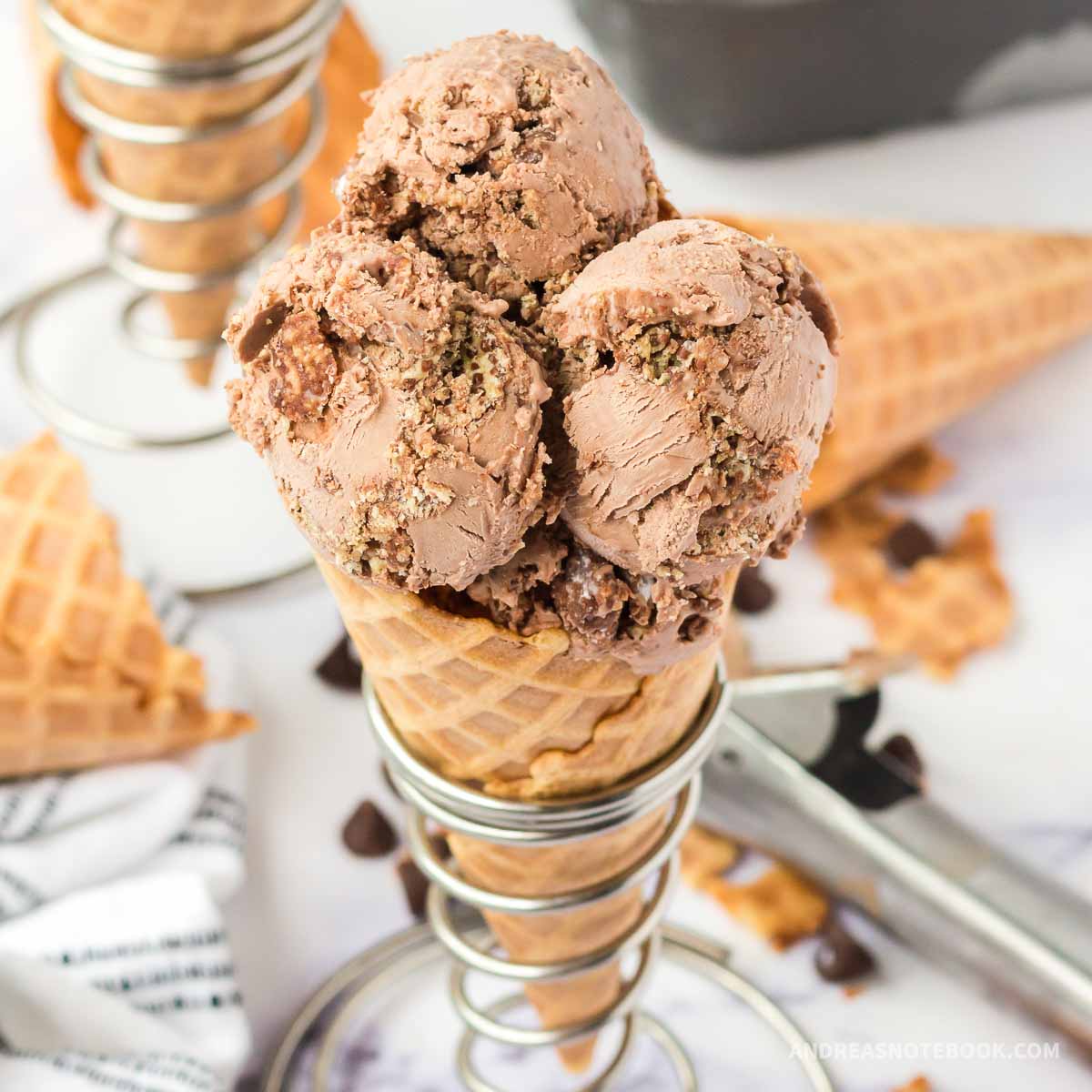 Triple scoop of muddy buddy ice cream on an ice cream cone.