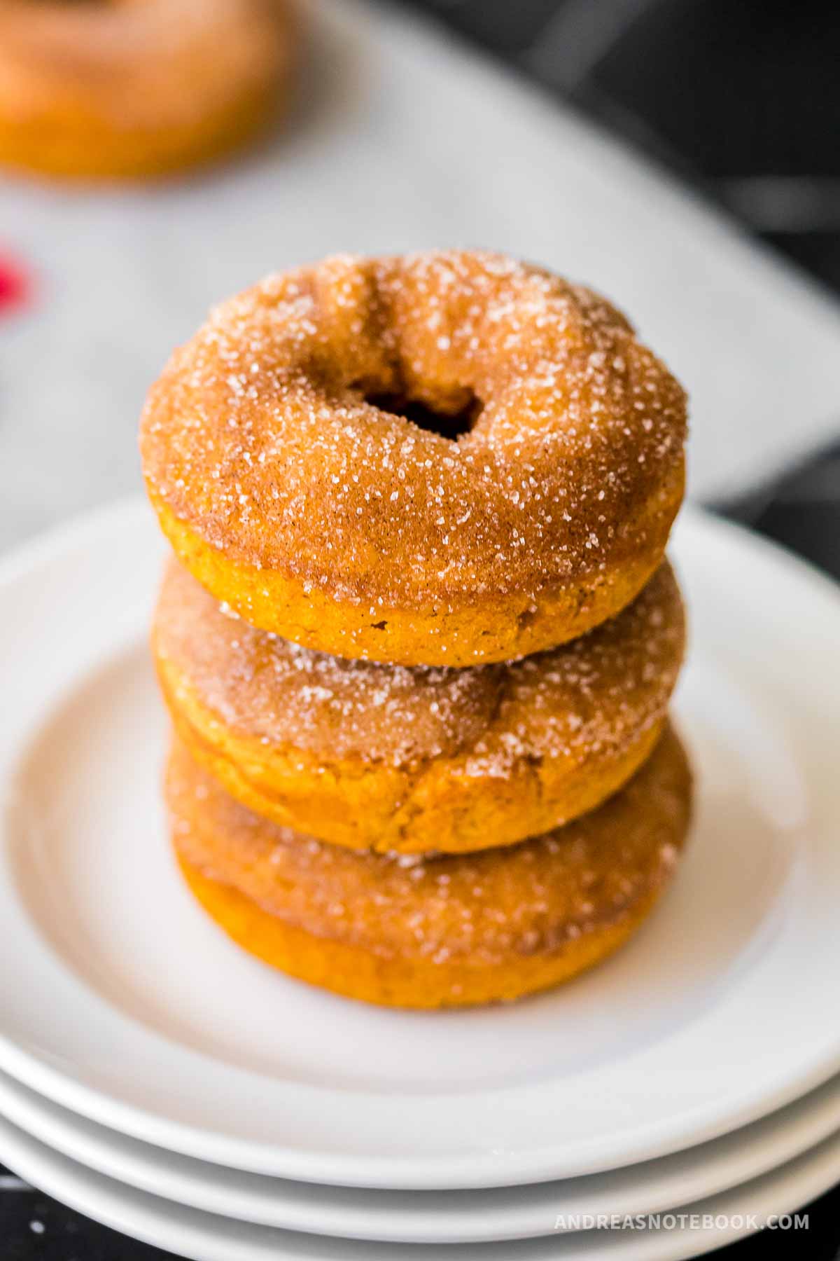 Stack of pumpkin spice donuts with cinnamon and sugar topping.