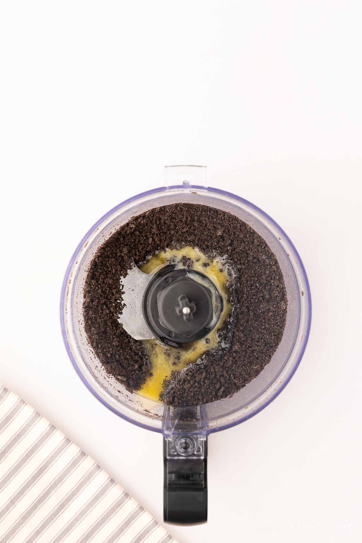 Butter added to Oreo crumbles in a food processor.