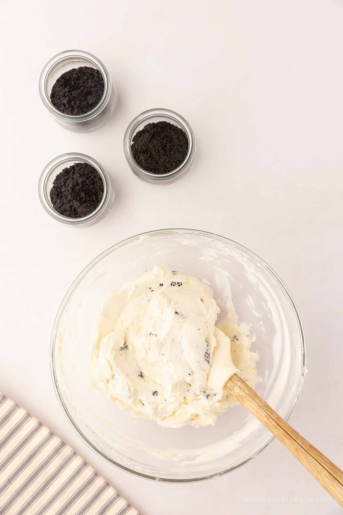 Whipped cream, cream cheese mixture and oreo crumbles in a bowl.