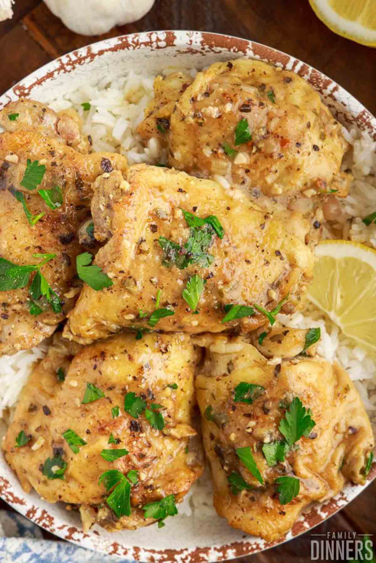 Stack of lemon butter chicken thighs cooked in an Instant Pot, resting on a bed of rice.