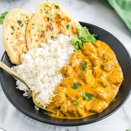 Bowl of butter chicken and rice with naan.