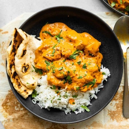 Bowl of chicken tikka masala with rice and naan.