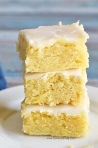 Stack of lemon gluten free blondies (brownies) with white frosting on top.