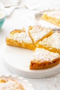 Round Belgian lemon tea cake cut into wedges on a plate with 4 wedges and 1 missing.