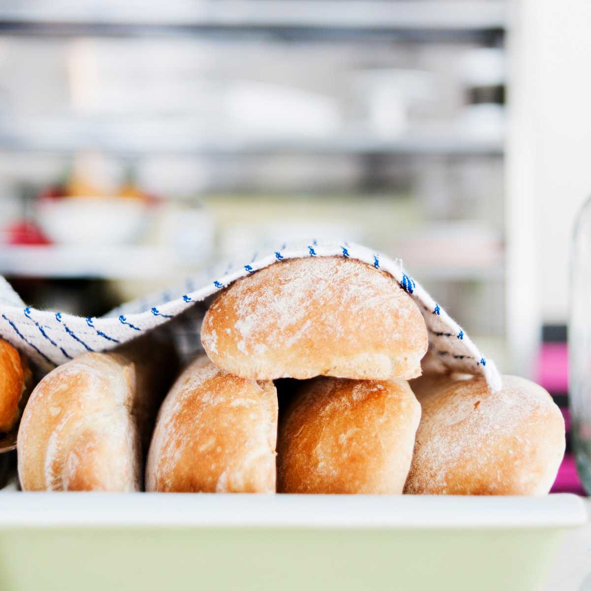 Fresh loaves of bread under a tea towel.