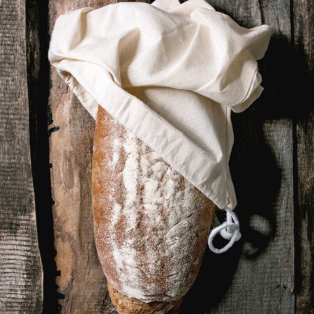 Artisan loaf of bread stored in a cloth bread bag.