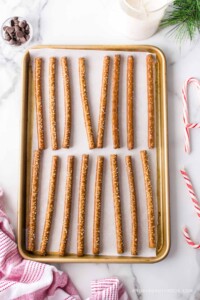 Pretzel rods lined up on a baking sheet covered in parchment paper.