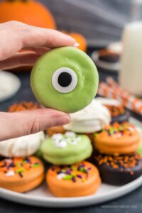 Cute one eyed monster halloween dipped oreo being held in a hand.