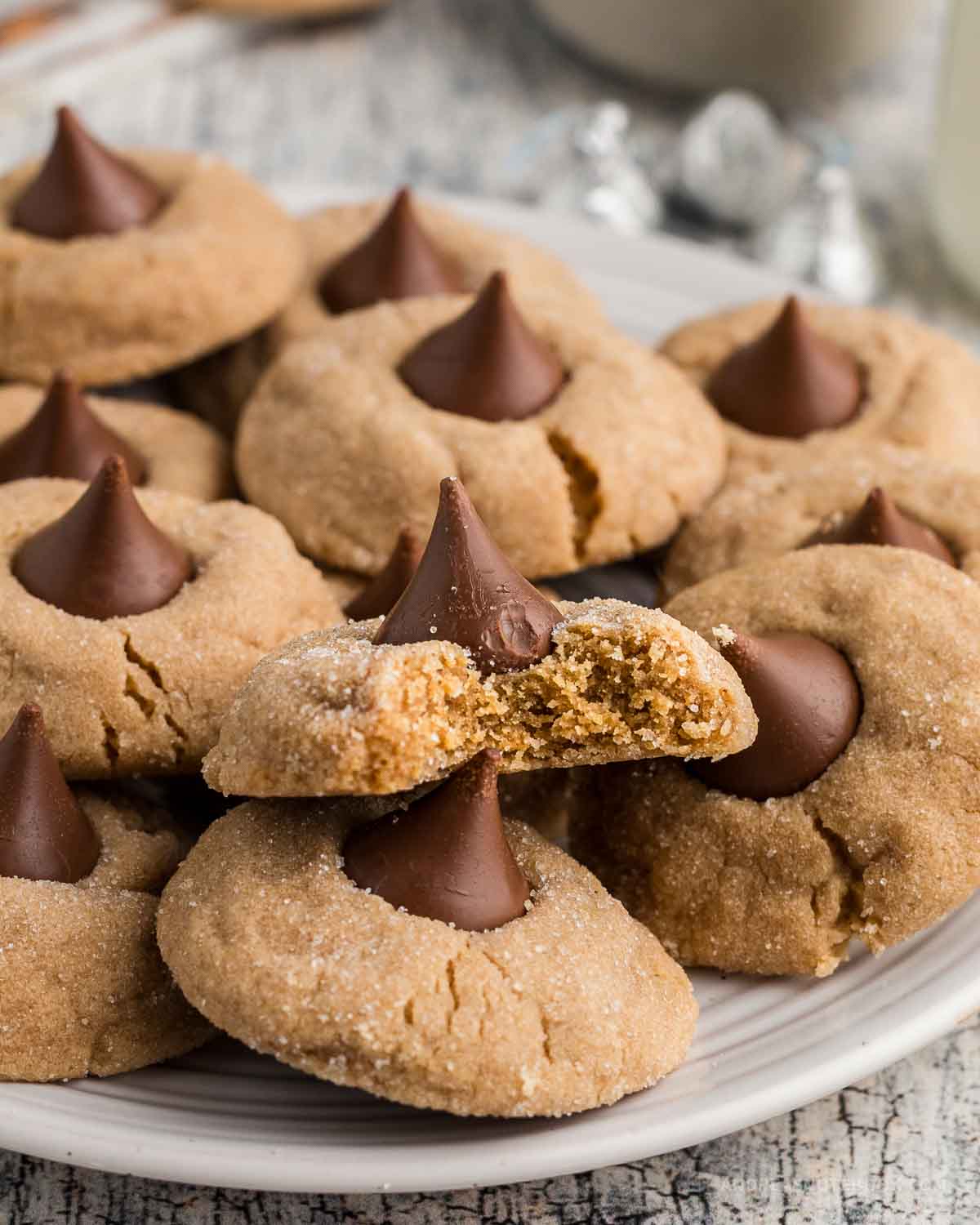 Plate full of peanut butter blossom cookies stacked on top of one another.