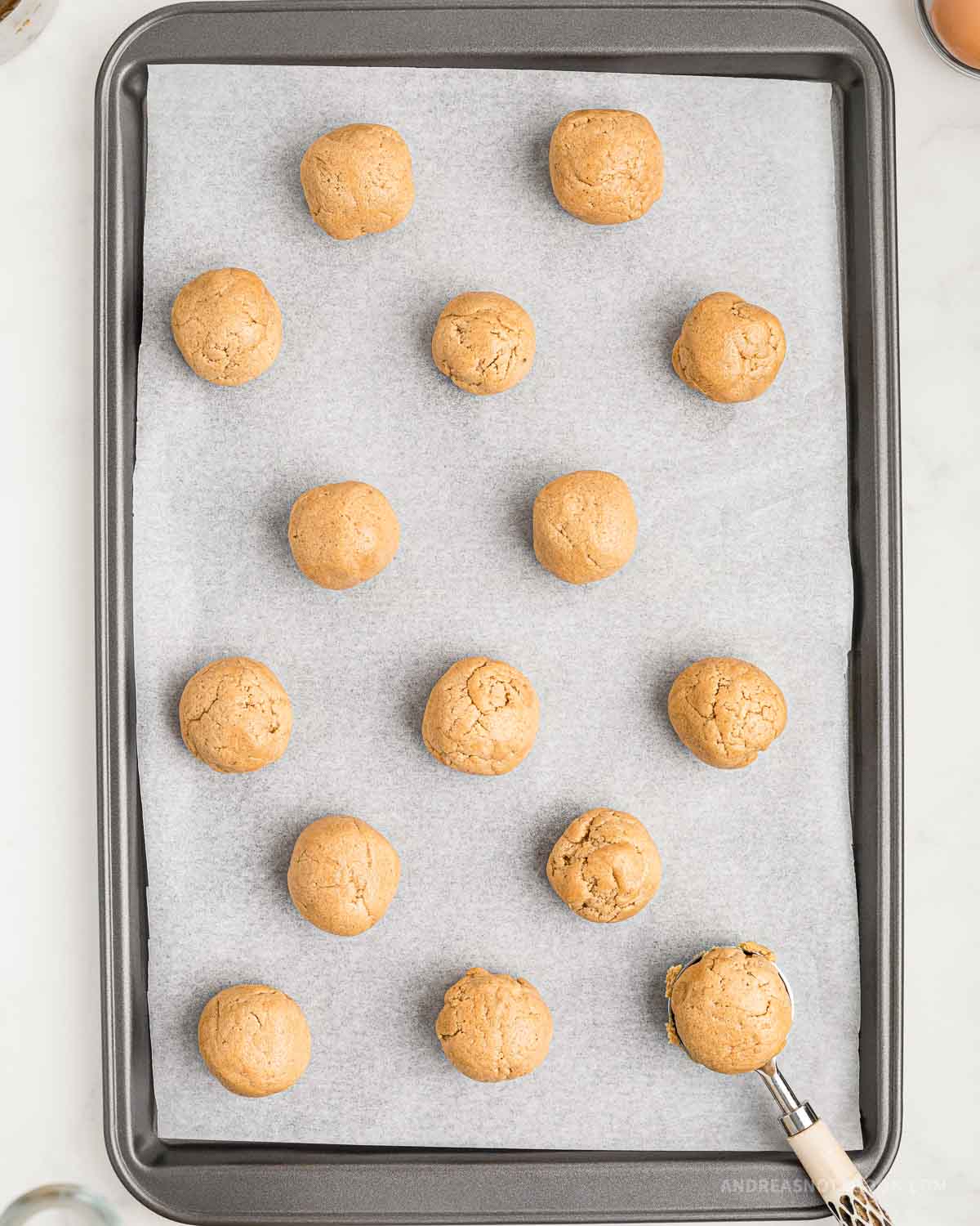 Balls of peanut butter cookies on a baking sheet.