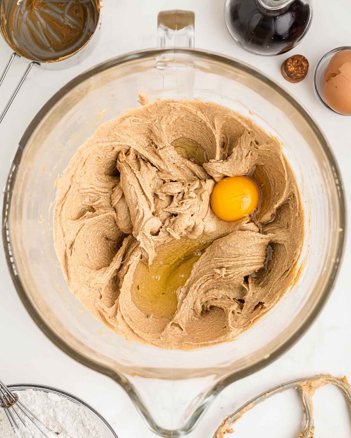 Mixed wet ingredients in a mixing bowl with egg on top.