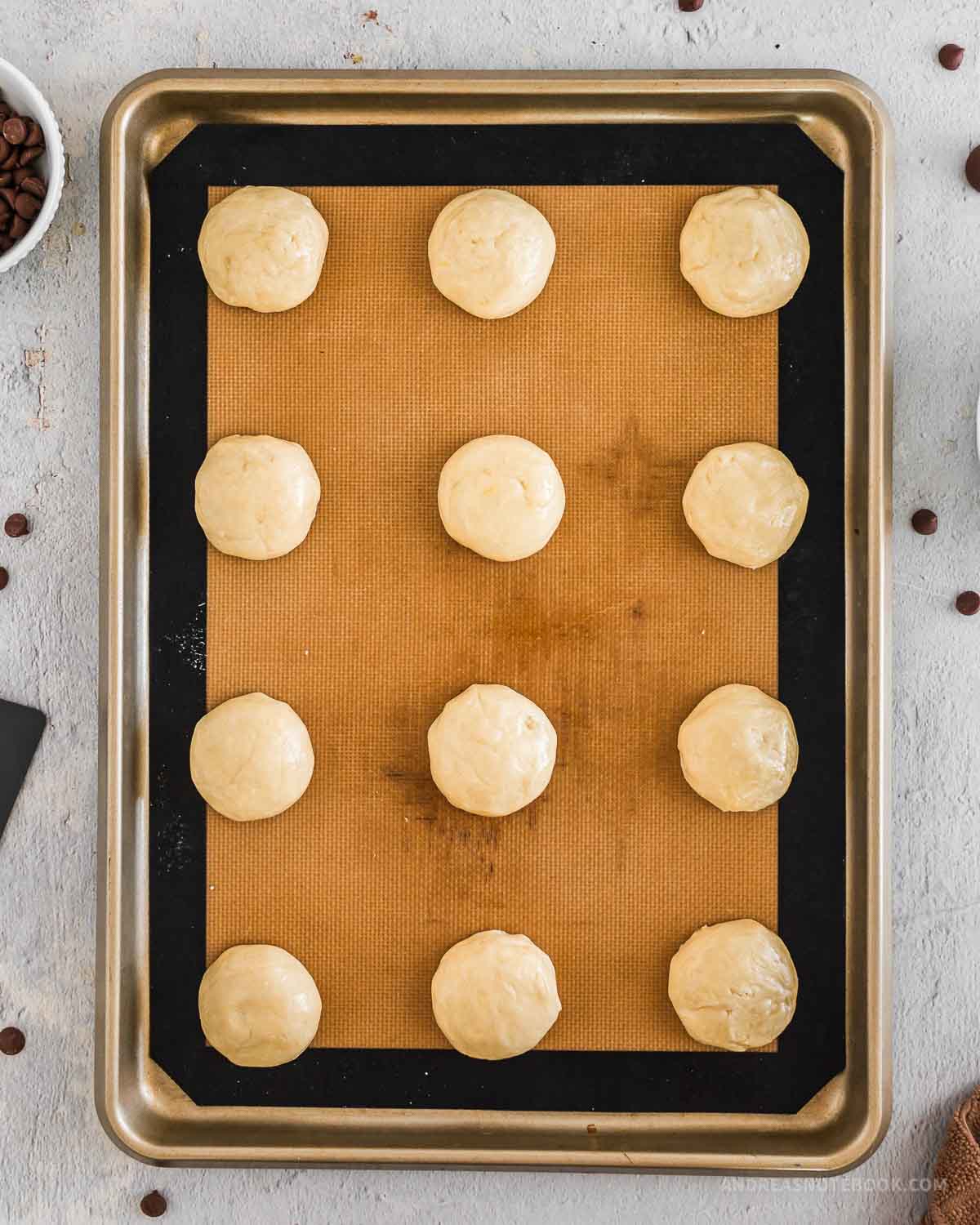 Baking sheet with 12 round cookie dough balls.