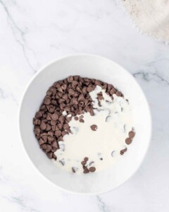 Cream and chocolate chips in a microwave safe bowl.