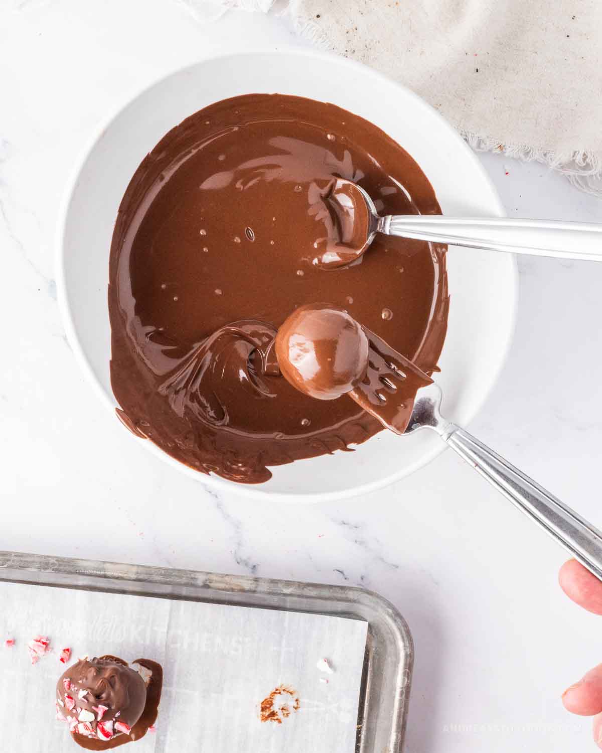Fork dipping round truffle ball into chocolate coating.