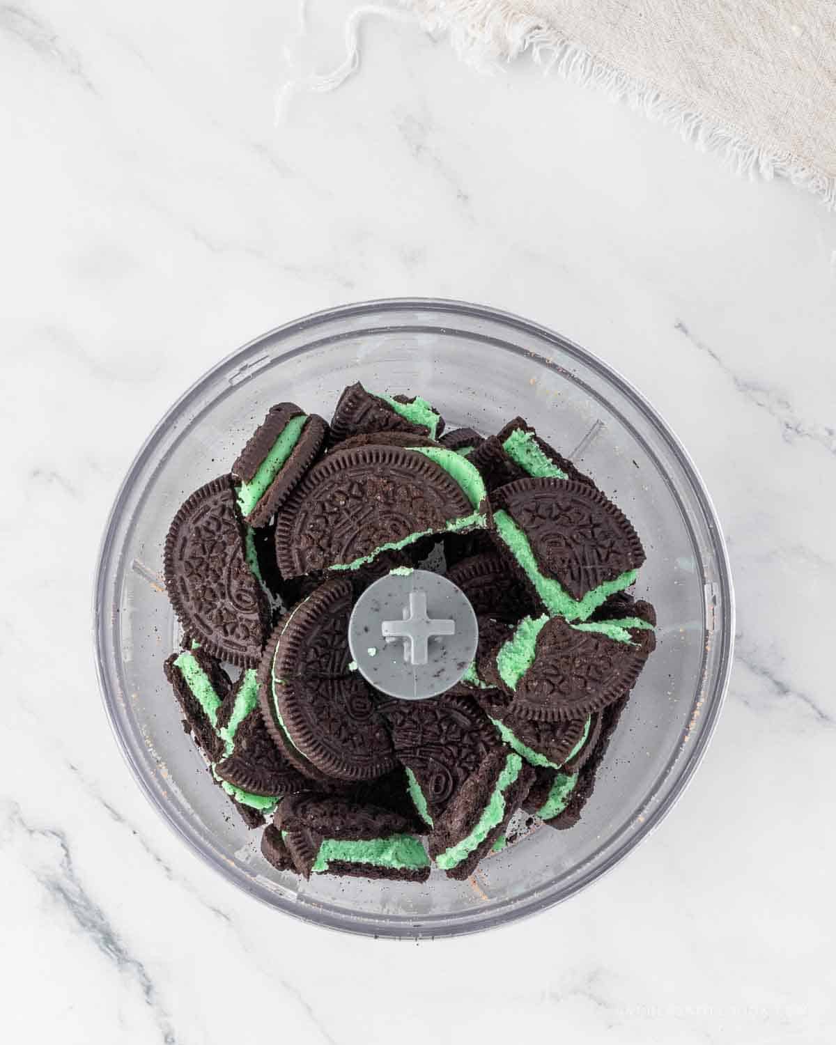 Mint oreos in a food processor before being ground up.