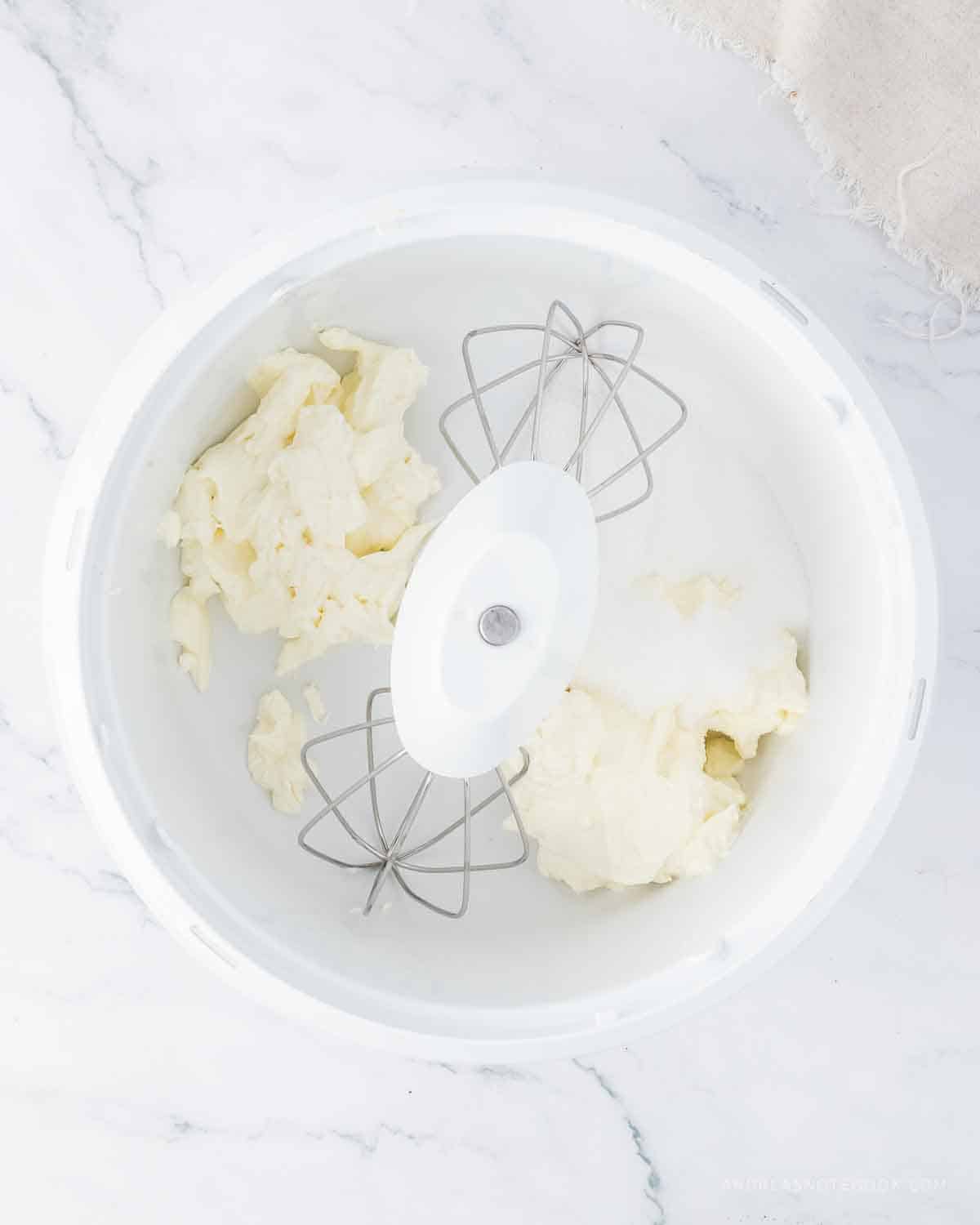 Cream cheese and sugar in a stand mixer bowl.