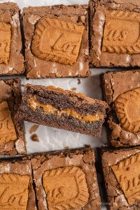 Cut squares of Biscoff cookie brownies with center one on it's side so you can see the layer of gooey cookie butter inside.