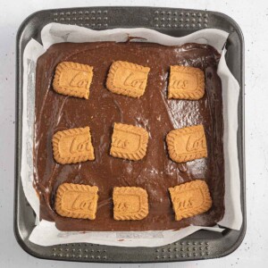 Brownie pan with brownie batter and halves of Biscoff cookies on top.
